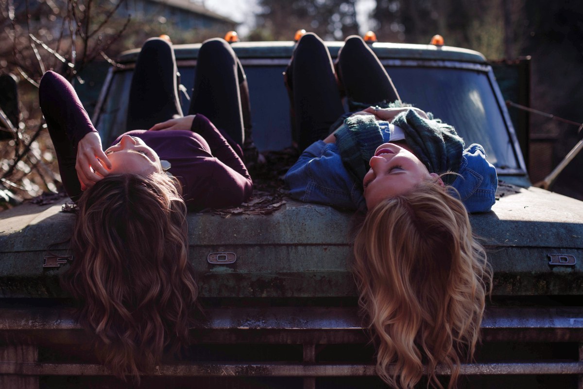 أصدقاء مستلقي على غطاء محرك السيارة